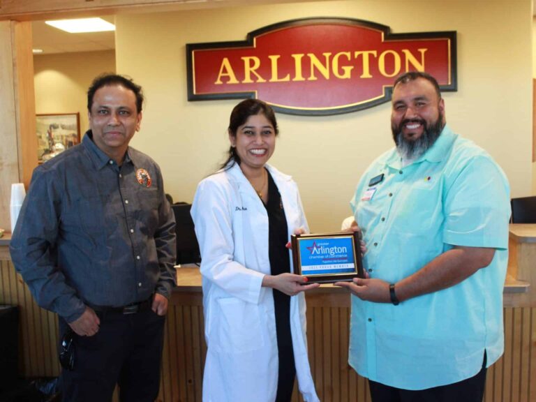 Dr. Priyanka Kulkarni poses with two gentlemen while holding a plaque from the city of Arlington