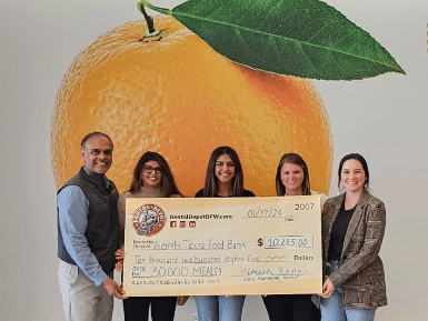 Dental Depot DFW employees present donor check in front of a giant peach design for the North Texas Food Bank.