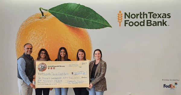 Dental Depot DFW employees present donor check in front of a giant peach design for the North Texas Food Bank.