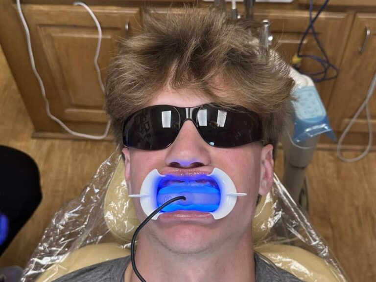 Young man gets his teeth whitened while wearing sunglasses.