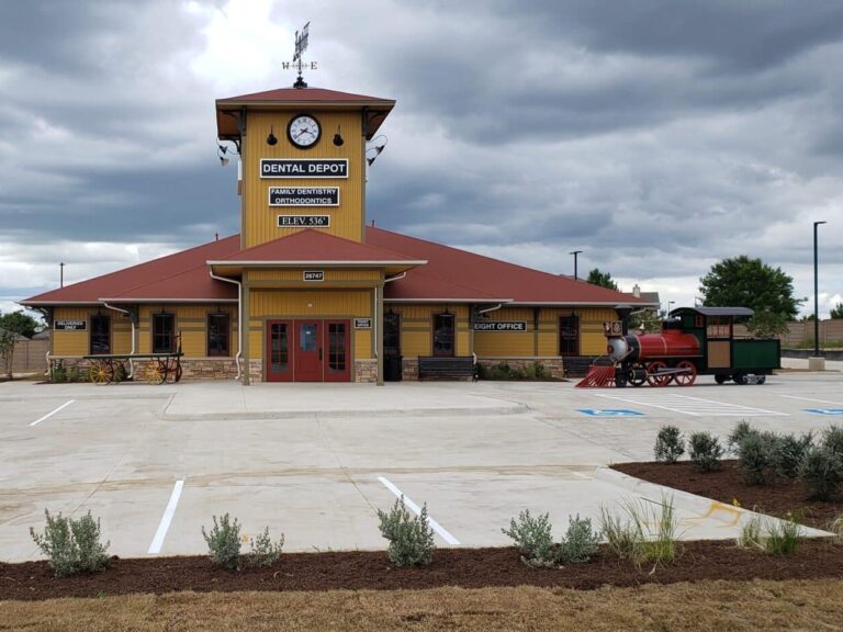 Front exterior view of Dental Depot's Aubrey dentist office with a red roof and yellow exterior.