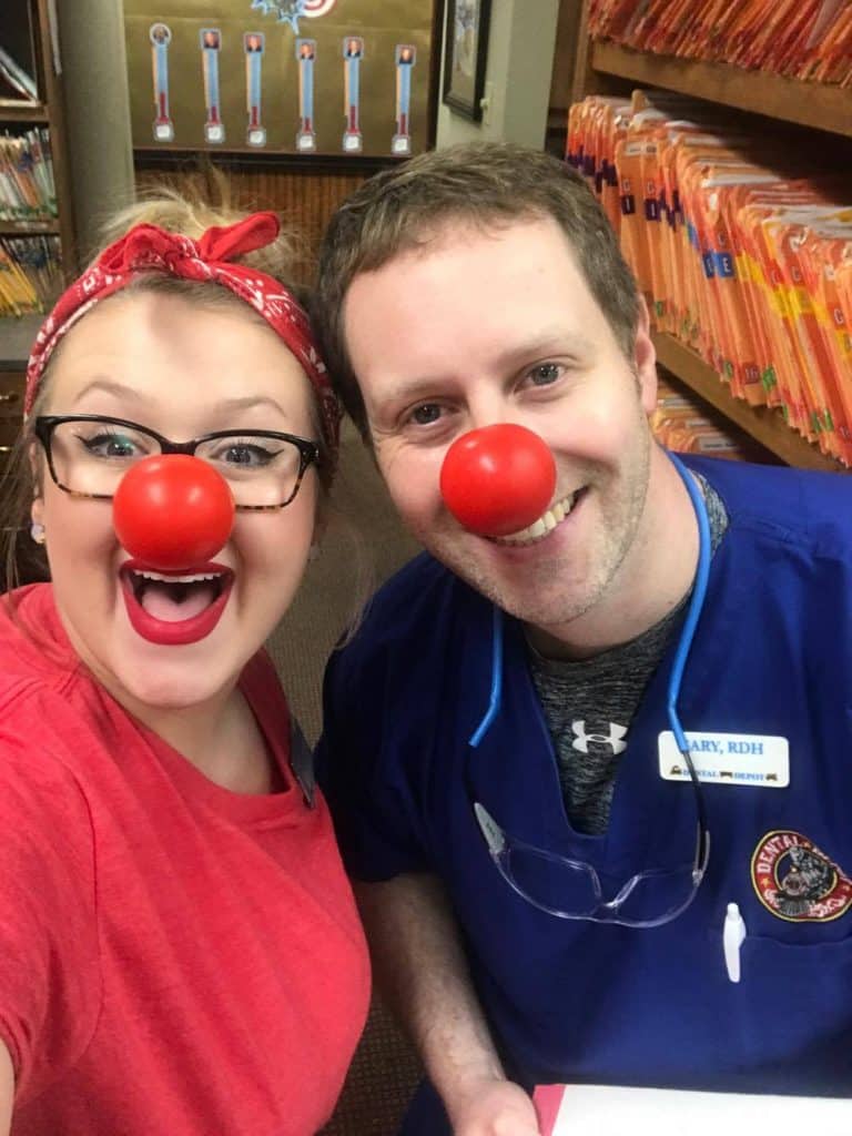 two dental assistants wearing clown noses in their scrubs
