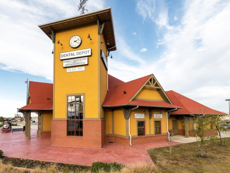 Exterior view of Dental Depot's dentist office in The Colony, TX with a yellow exterior, red roof, and clock tower.