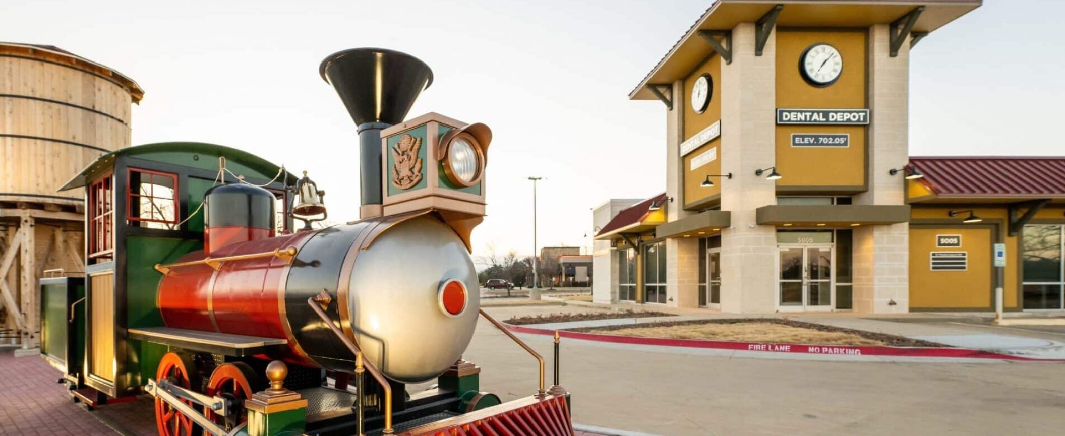 Exterior view of the new Dental Depot dental office in Arlington with the Dental Depot train in the foreground and the dental clinic and water tower in the background.