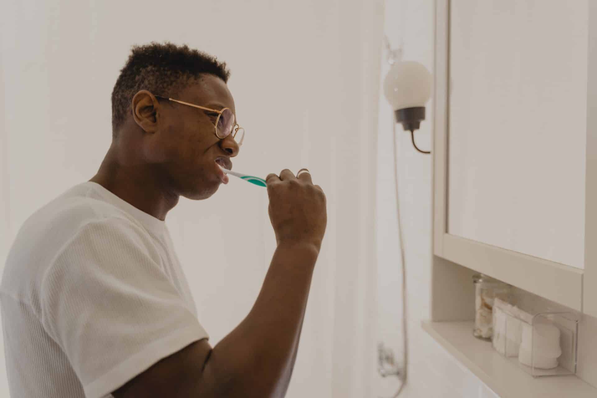 Image of a man brushing his teeth while looking in the mirror